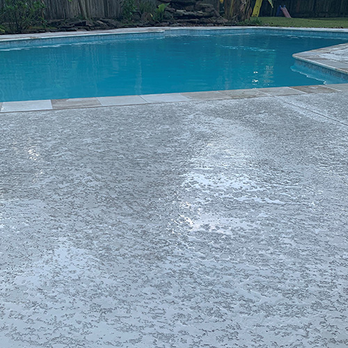 A modern pool with custom concrete deck coating in Houston, designed by Houston Pool Renovations