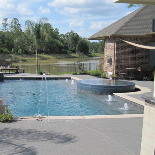 A modern pool with custom concrete deck coating in Houston, designed by Houston Pool Renovations