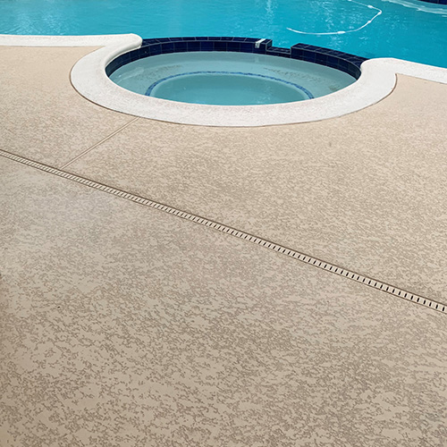 A modern pool with custom concrete deck coating in Houston, designed by Houston Pool Renovations