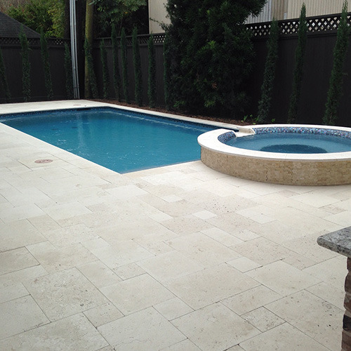 A custom deck featuring natural stone pavers, designed and installed by Houston Pool Renovations, adding elegance to a backyard space.