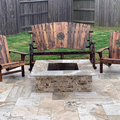 A custom-built stone fire pit near a pool in Houston, surrounded by elegant outdoor seating, designed by Houston Pool Renovations.