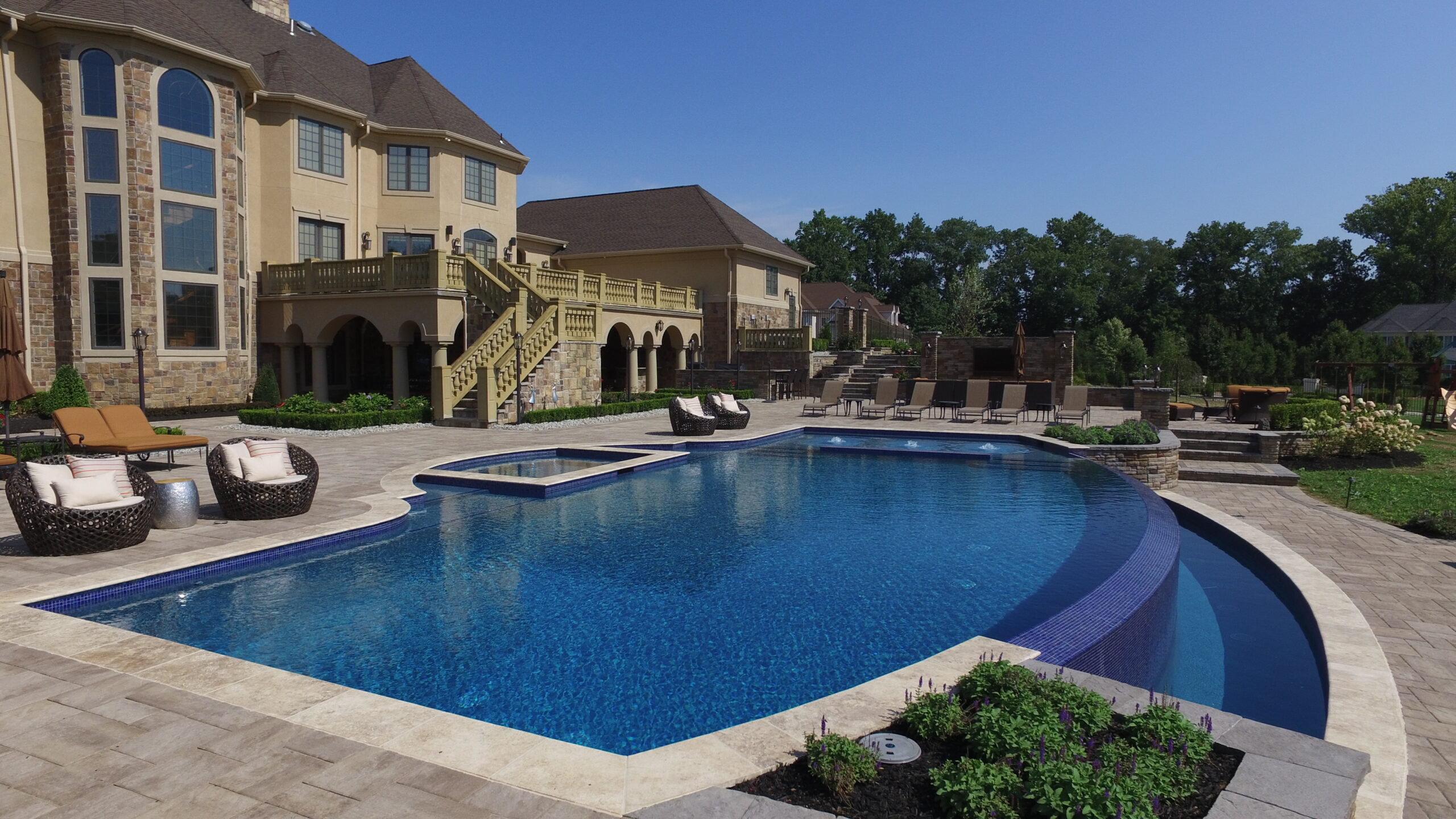 A beautifully remodeled pool in Houston, surrounded by lush landscaping, showcasing the quality work of Houston Pool Renovations.