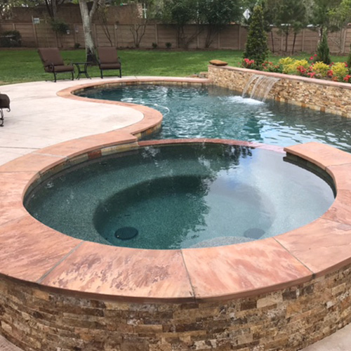 A beautifully remodeled pool in Houston, surrounded by lush landscaping, showcasing the quality work of Houston Pool Renovations.