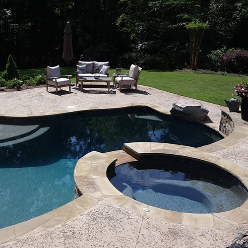 A beautifully remodeled pool in Houston, surrounded by lush landscaping, showcasing the quality work of Houston Pool Renovations.